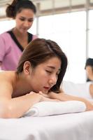 porträtt av ung vacker asiatisk kvinna njuter av massage i en lyxig kurort foto