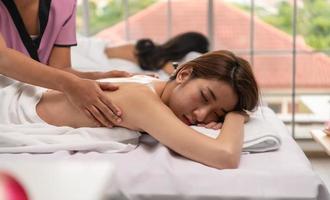 porträtt av ung vacker asiatisk kvinna njuter av massage i en lyxig kurort foto