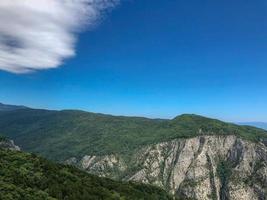 blå himmel vita moln på kullen, berg med utsikt över träd. foto