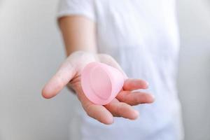 kvinna hand som håller rosa menskopp isolerad på vit bakgrund. kvinna modern alternativ eko gynekologisk hygien under menstruation. behållare för blod i flickans hand. foto
