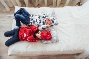 barn i mjuk varm pyjamas som leker i sängen foto