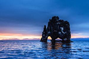 hvitserkur 15 m höjd. är en spektakulär sten i havet på islands norra kust. detta foto reflekteras i vattnet efter midnattssolnedgången.
