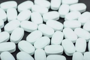 medicinska vita tabletter eller kosttillskott för behandling och hälsovård på svart bakgrund foto