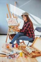 kreativ eftertänksam målarflicka målar en färgstark bild på duk med oljefärger i verkstad foto