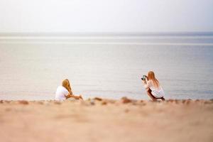 fotograf fotograferar älskande par i kärlek på sandstrand, havsbild horisont bakgrund utomhus foto