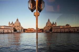 utsikt och reflektion i glaset av den gamla katedralen i santa maria della salute vid solnedgången i Venedig, Italien foto