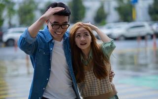 unga asiatiska par går i regnet foto