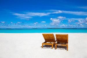 två solstolar på den tropiska sandstranden, panorama perfekt för banderoller. vacker strand. stolar på sandstranden nära havet. sommar semester semester koncept turism. inspirerande tropiska landskap foto