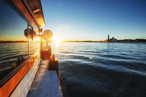 utsikt och reflektion i glaset av den gamla katedralen i santa maria della salute vid solnedgången i Venedig, Italien foto