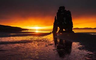 är en spektakulär sten i havet på islands norra kust. legender säger att det är ett förstenat troll. på denna bild reflekterar hvitserkur i havsvattnet efter midnattssolnedgången. foto
