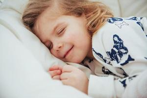 barn liten flicka sover i sängen foto