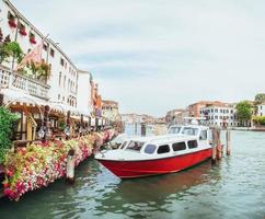 grön vattenkanal med gondoler och färgglada fasader av gamla medeltida byggnader i solen i Venedig foto