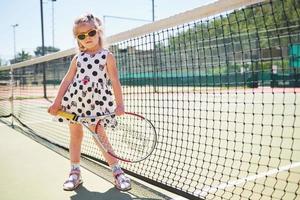 glad liten flicka spelar tennis foto