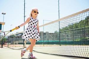 söt tjej spelar tennis och poserar för kameran foto