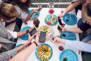 glada unga vänner satt vid ett bord och hade picknick utomhus foto