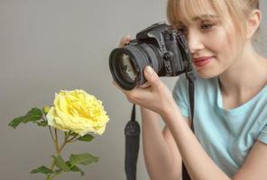ung kvinna fotograf skjuta en gul ros med digitalkamera. närbild, skytte, hobby, yrke koncept foto