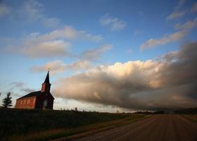 åska moln bildas bakom en landskyrka foto