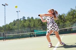 glad liten flicka spelar tennis foto