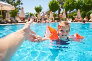 flicka simmar i poolen i armband på en varm sommardag. foto