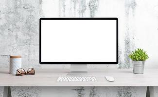 datorskärm på skrivbordet med isolerad skärm för mockup, wep-sidapresentation. rent skrivbord med växt, glas och låda. vit grov vägg i bakgrunden