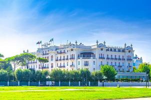 storslagen hotellbyggnad och torg med grön gräsmatta i turistiska stadscentrum med blå himmel bakgrund i solig sommardag foto