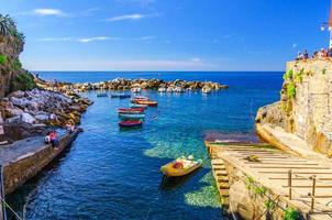 färgglada fiskebåtar på genomskinligt vatten i liten hamn i riomaggiore by nationalpark cinque terre foto