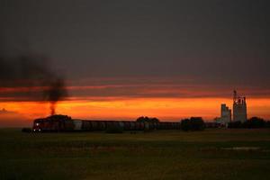 tåg passerar genom ögonbryn saskatchewan vid solnedgången foto