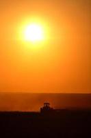 solnedgången bakom jordbruket arbetar hans fält foto