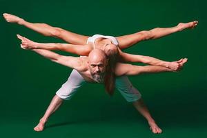 vacker sportig kvinna och man i vita kläder gör yoga asanas tillsammans inomhus på grön bakgrund foto