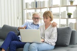 lyckliga kaukasiska senior par använder laptop hemma foto