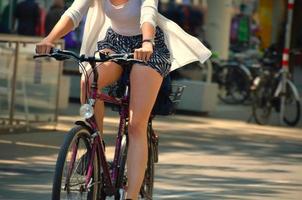 kvinna med kort kjol cyklar i staden foto