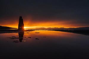 är en spektakulär sten i havet på Islands norra kust. legender säger att det är ett förstenat troll. på detta foto reflekterar hvitserkur i havsvattnet efter midnattssolnedgången