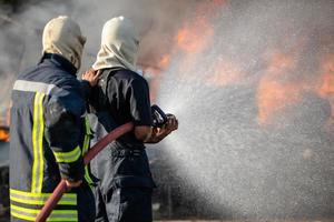 brandman sprutar vatten från en stor vattenslang för att förhindra brand foto