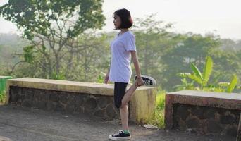 ung asiatisk kvinna har streaching innan du joggar och springer på morgonen foto