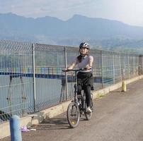 ung asiatisk kvinna cyklar på sommaren foto