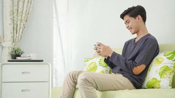 ung asiatisk man spelar spel på smartphone hemma foto