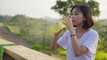 ung asiatisk kvinna har dricka och paus efter jogging på morgonen foto