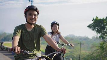 unga asiatiska par cyklar tillsammans på morgonen foto