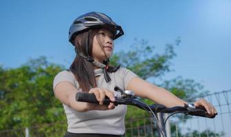 ung asiatisk kvinna njuter av cykling på sommarmorgonen foto