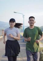 unga asiatiska par i sportiga kläder kör tillsammans på morgonen foto