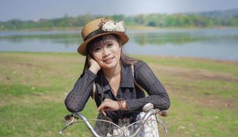 ung asiatisk kvinna njuter av att cykla medan hon stannar vid parken foto