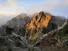 fantastisk, solnedgång över en pyramidformad bergstopp. vackert gyllene orange solljus. resa världen runt. nomadliv. äventyrlig livsstil. högtider. vandring på ön madeira, portugal. foto