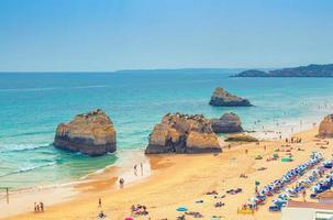 portimao, algarve, portugal, 19 juni 2017 turister som solar på vacker sandstrand praia dos tres castelos med klippor och klippor i algarvedistriktet foto