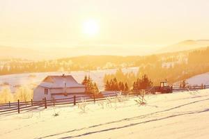 det mystiska vinterlandskapet är majestätiska berg på vintern. fantastisk solnedgång. spela in hus i snön. foto vykort. karpaterna
