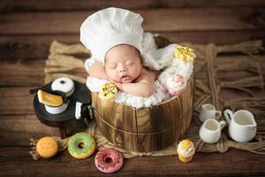 bedårande söt asiatisk nyfödd baby bär kock hatt sover foto