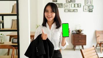 vacker ung asiatisk affärskvinna i kostym står på café med grön skärm telefon foto