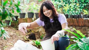 asiatisk kvinna förbereda en plats för plantering med kruka foto