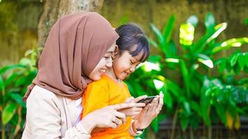 mor och dotter spelar telefonen i parken foto