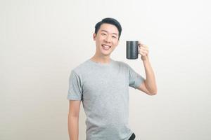 ung asiatisk man håller kaffekoppen foto