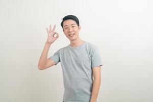 ung asiatisk man tummen upp eller ok hand tecken foto